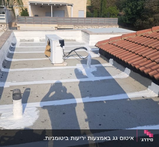 גג עם איטום לבן ומזגן על הגג